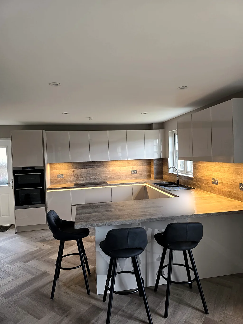 Handleless grey kitchen with breakfast bar and wood-effect worktops