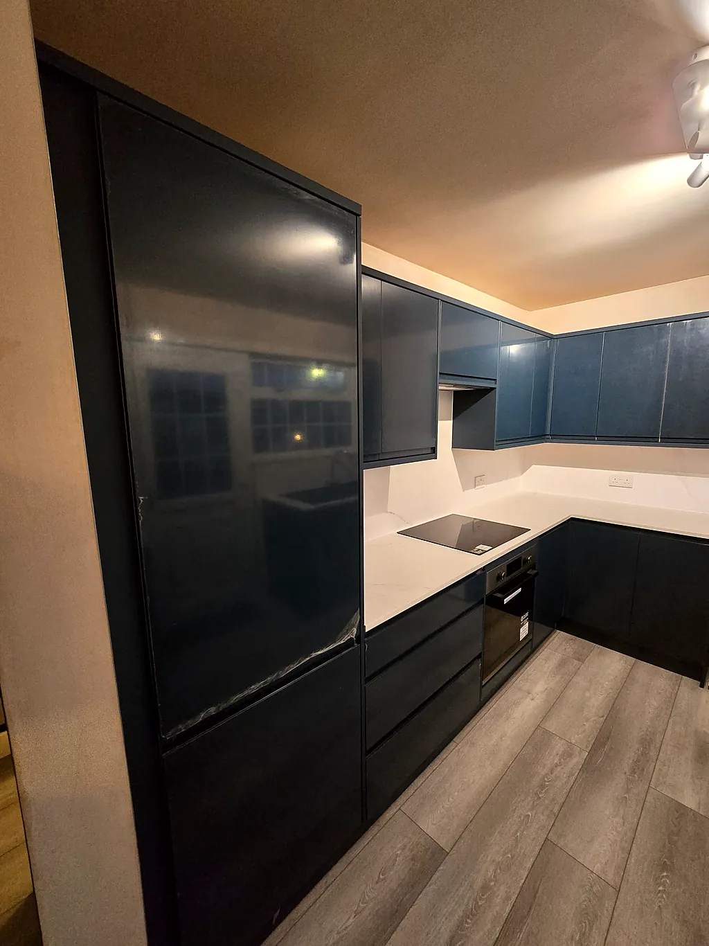 Navy handleless kitchen with marble worktop and splashback after renovation