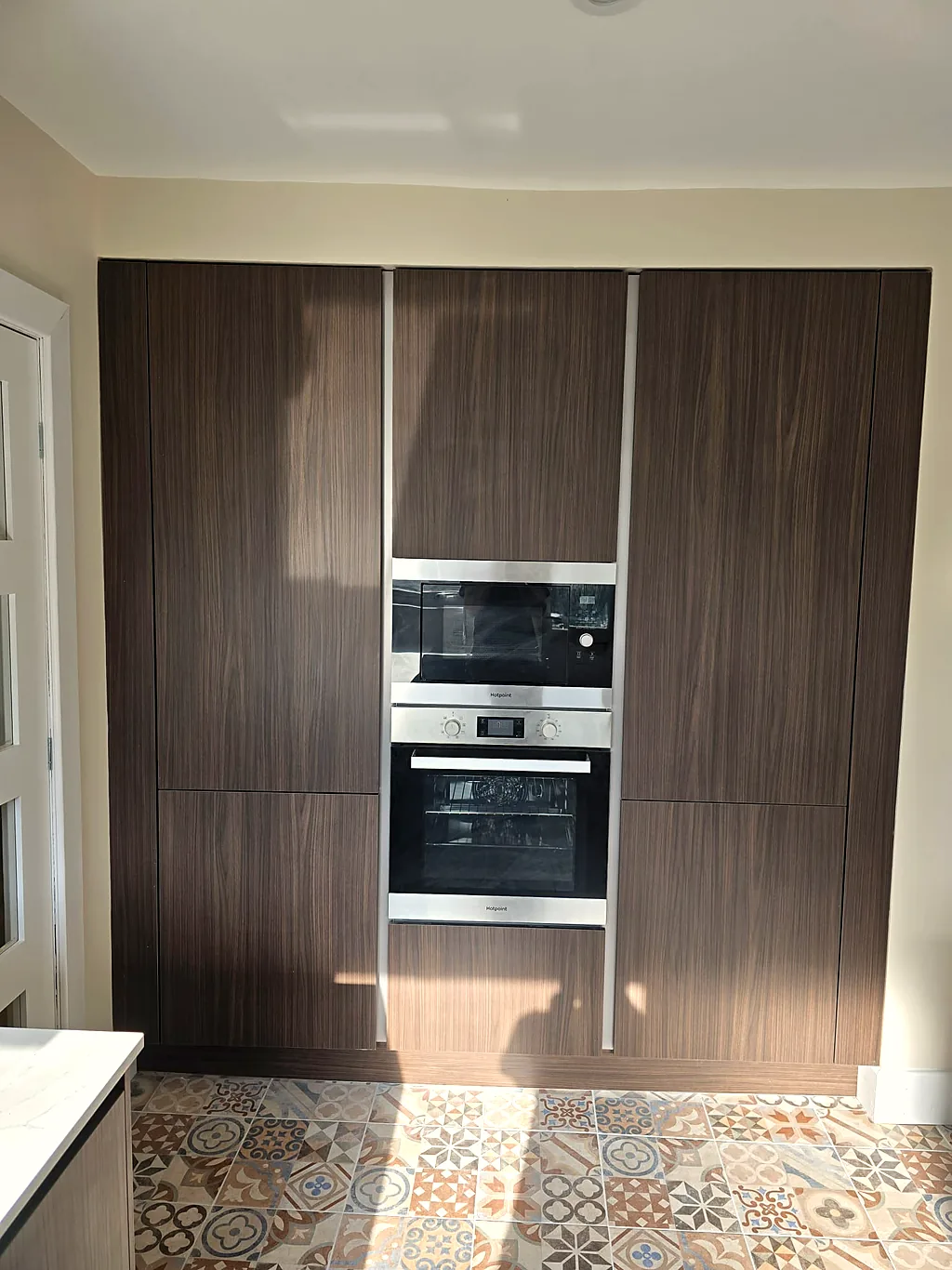 Walnut full-height units with integrated ovens after renovation
