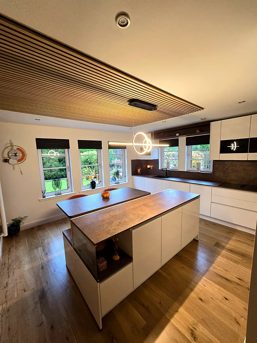 Modern kitchen with a large central island and timber-slatted ceiling