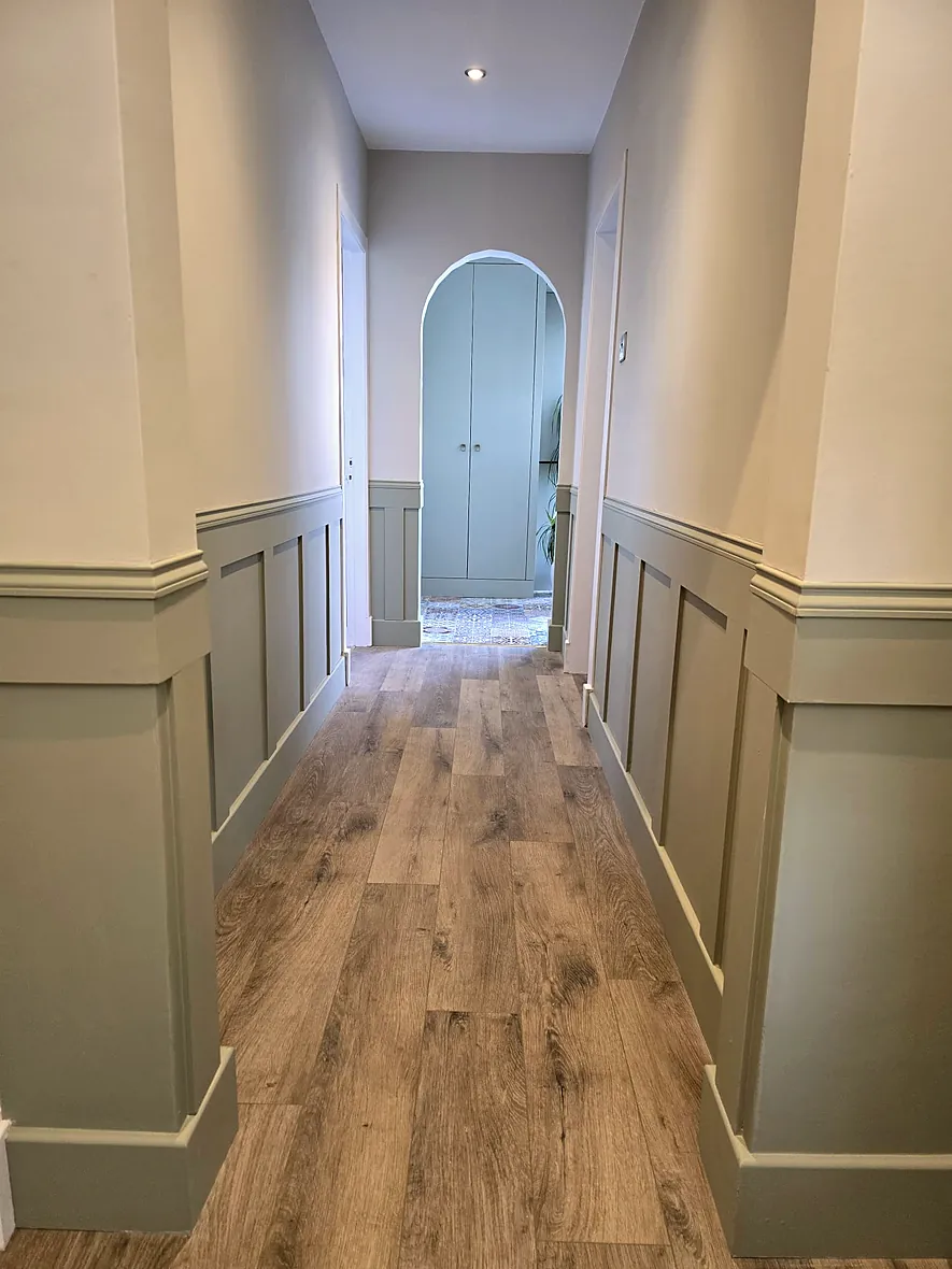 Bespoke sage-green wall panelling with oak-effect flooring