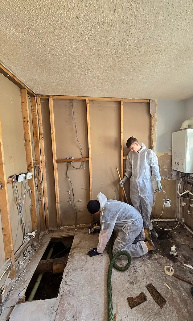 Joiners in protective gear lifting floors and exposing studwork